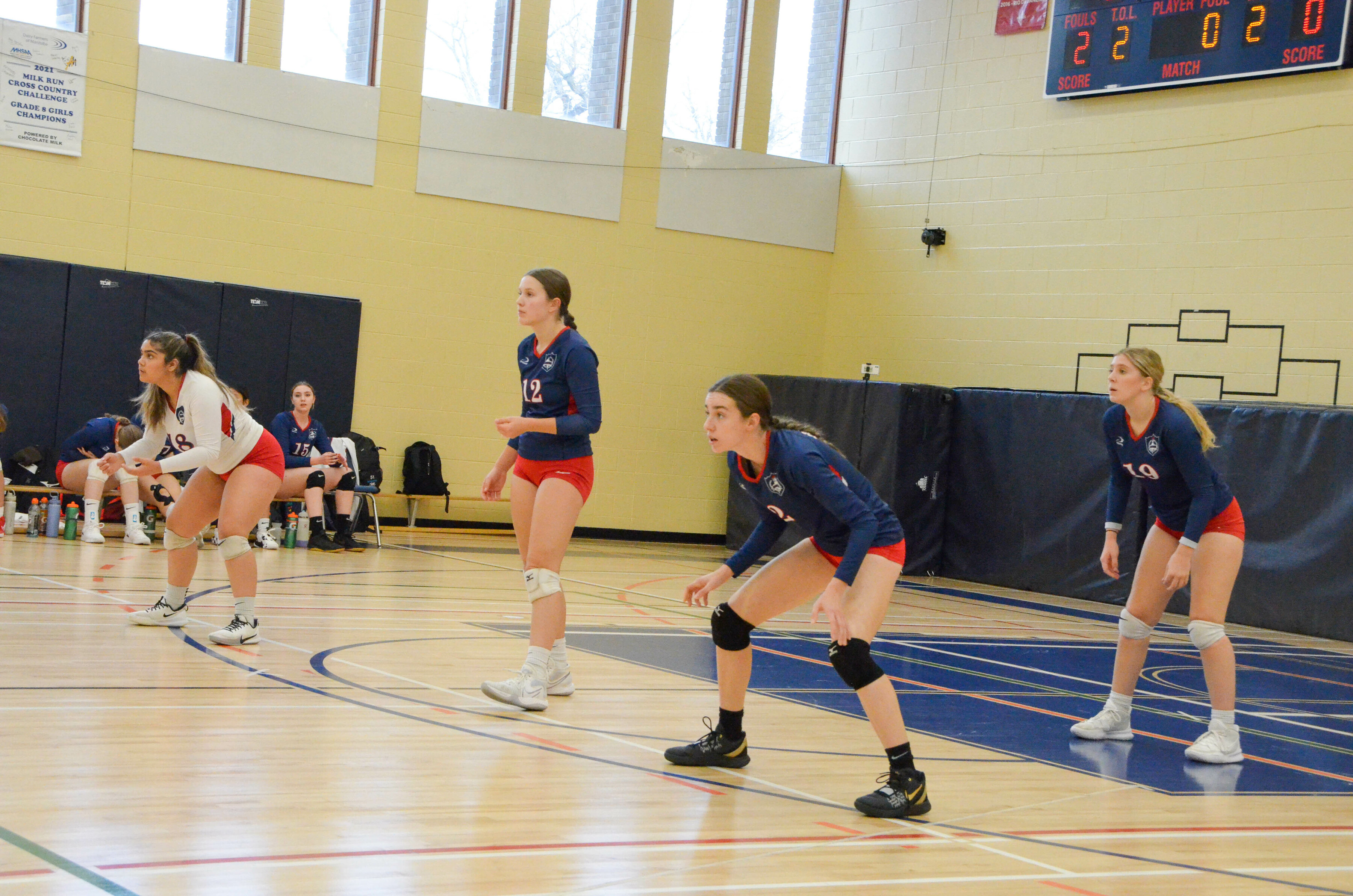 4 girls playing volleyball inside a gymnasium court