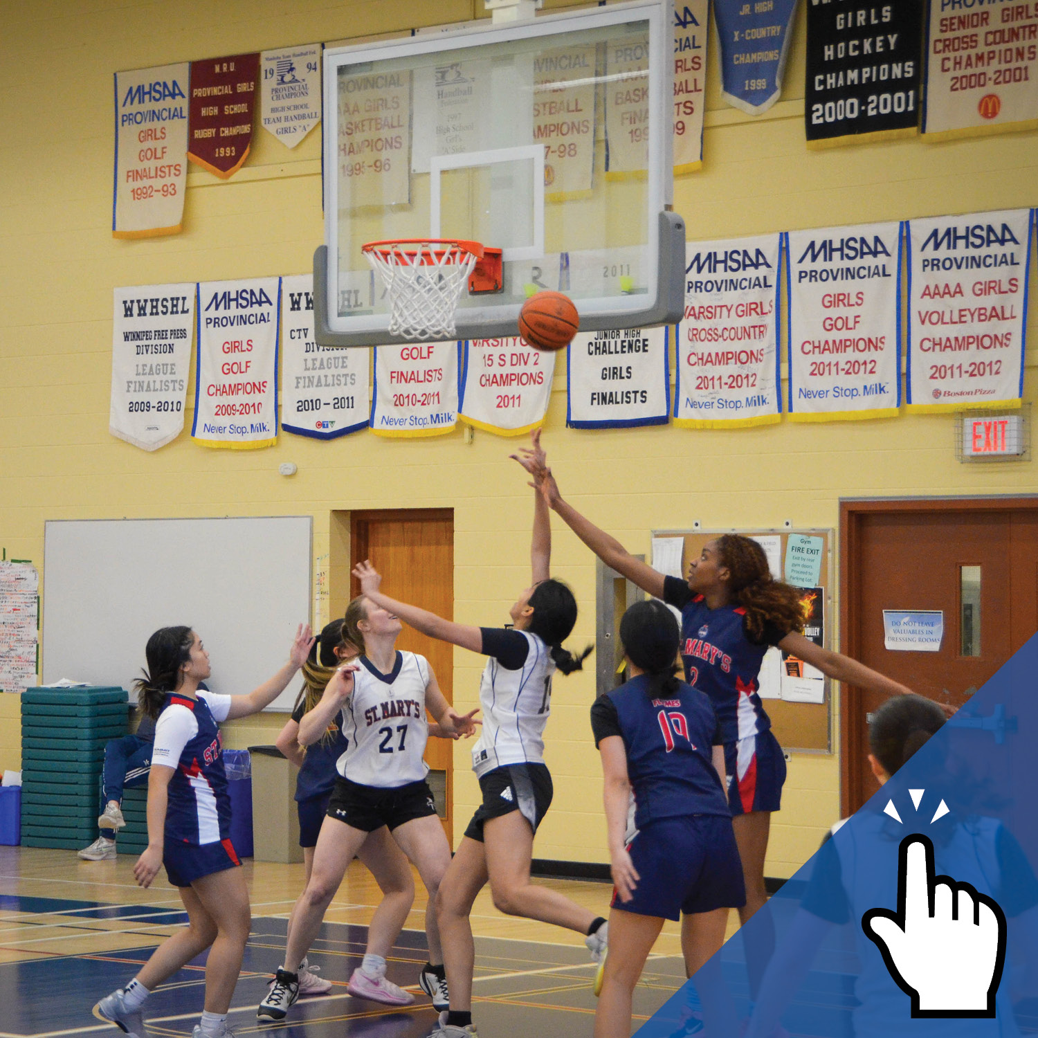 a group of students playing basketball with championship banners hung on the wall in the background.