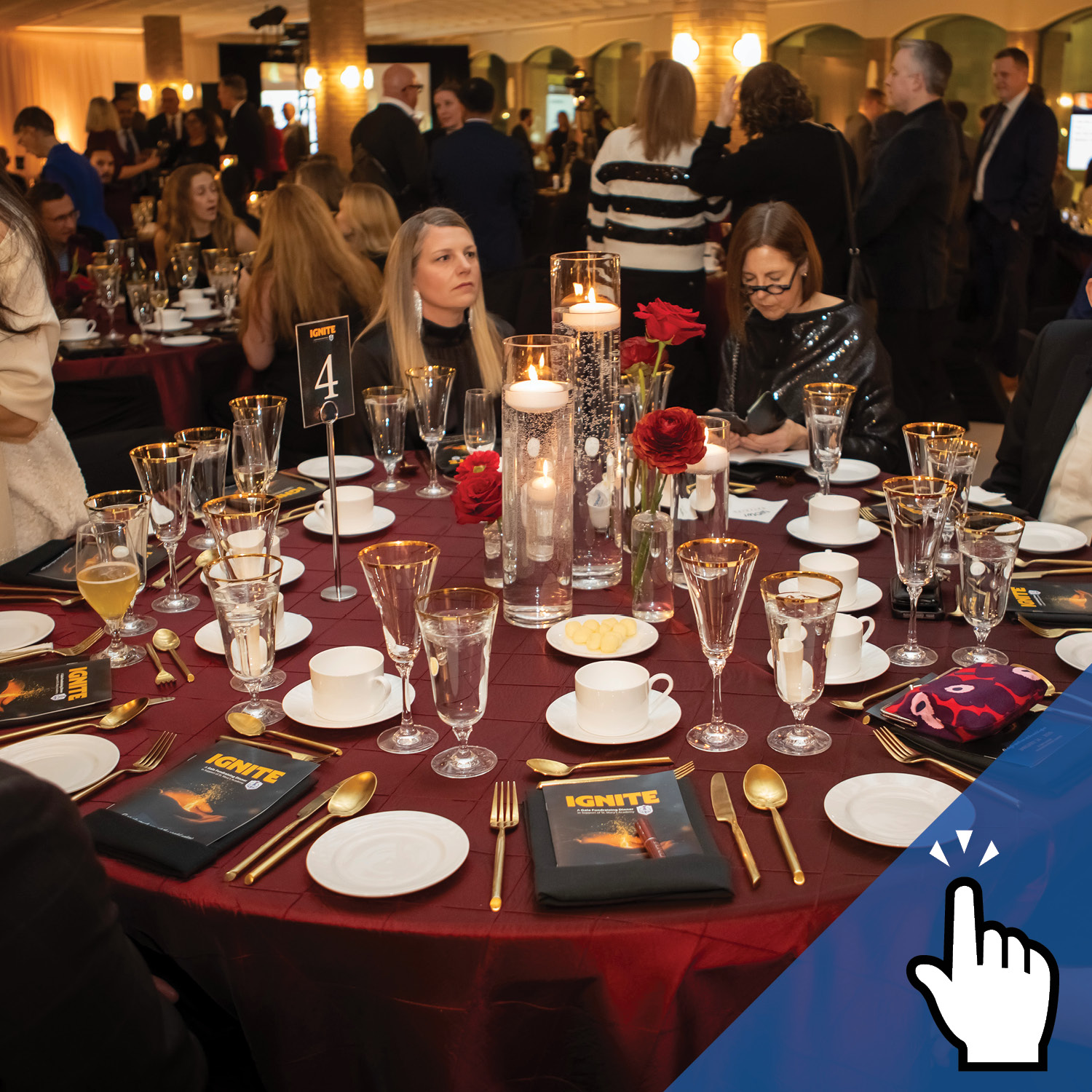 A group of people seated at a formal event with a fancy dinner table in the foreground.