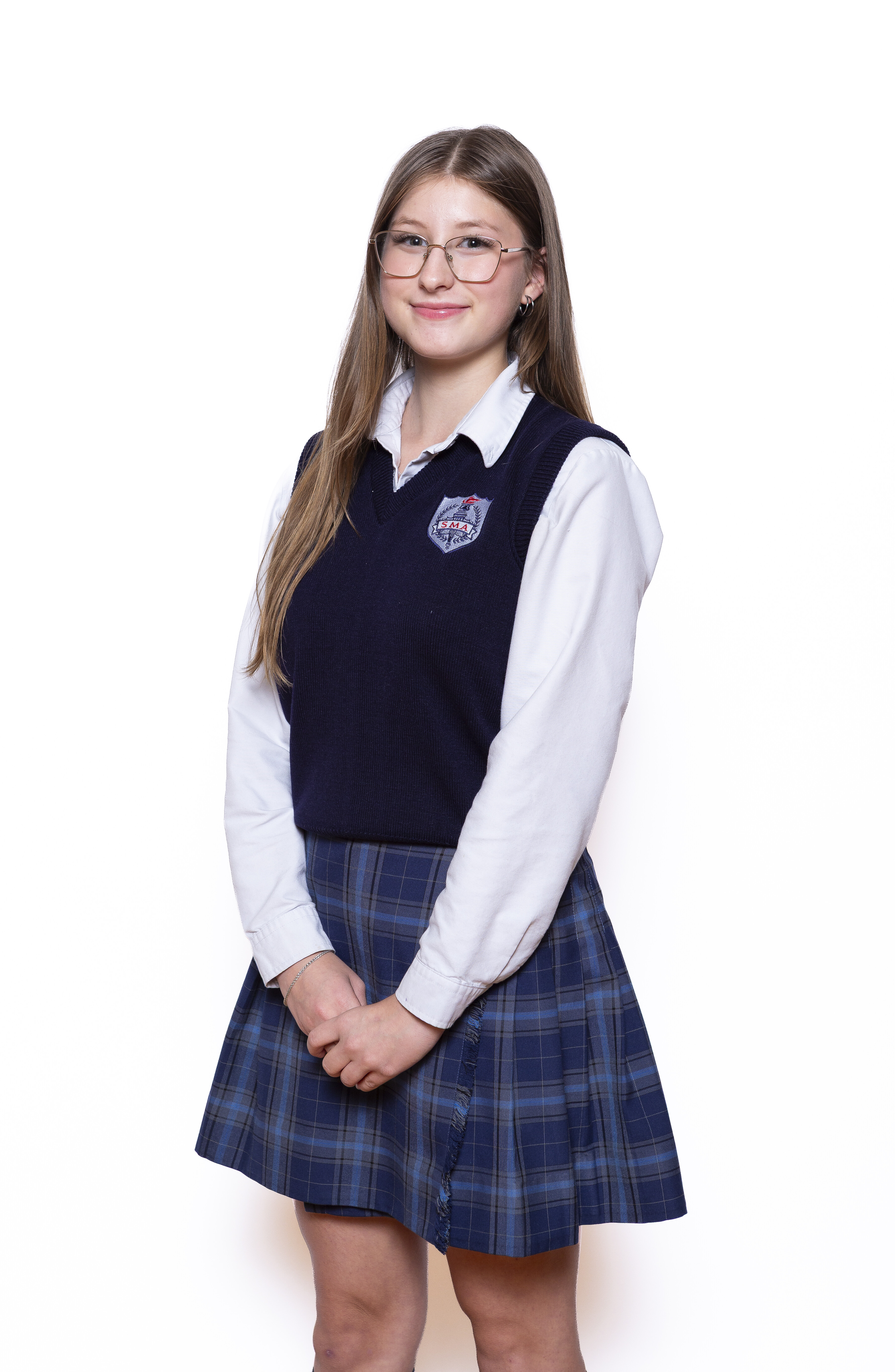 A uniformed student wears a plaid skirt, white button-down shirt and dark v-neck.