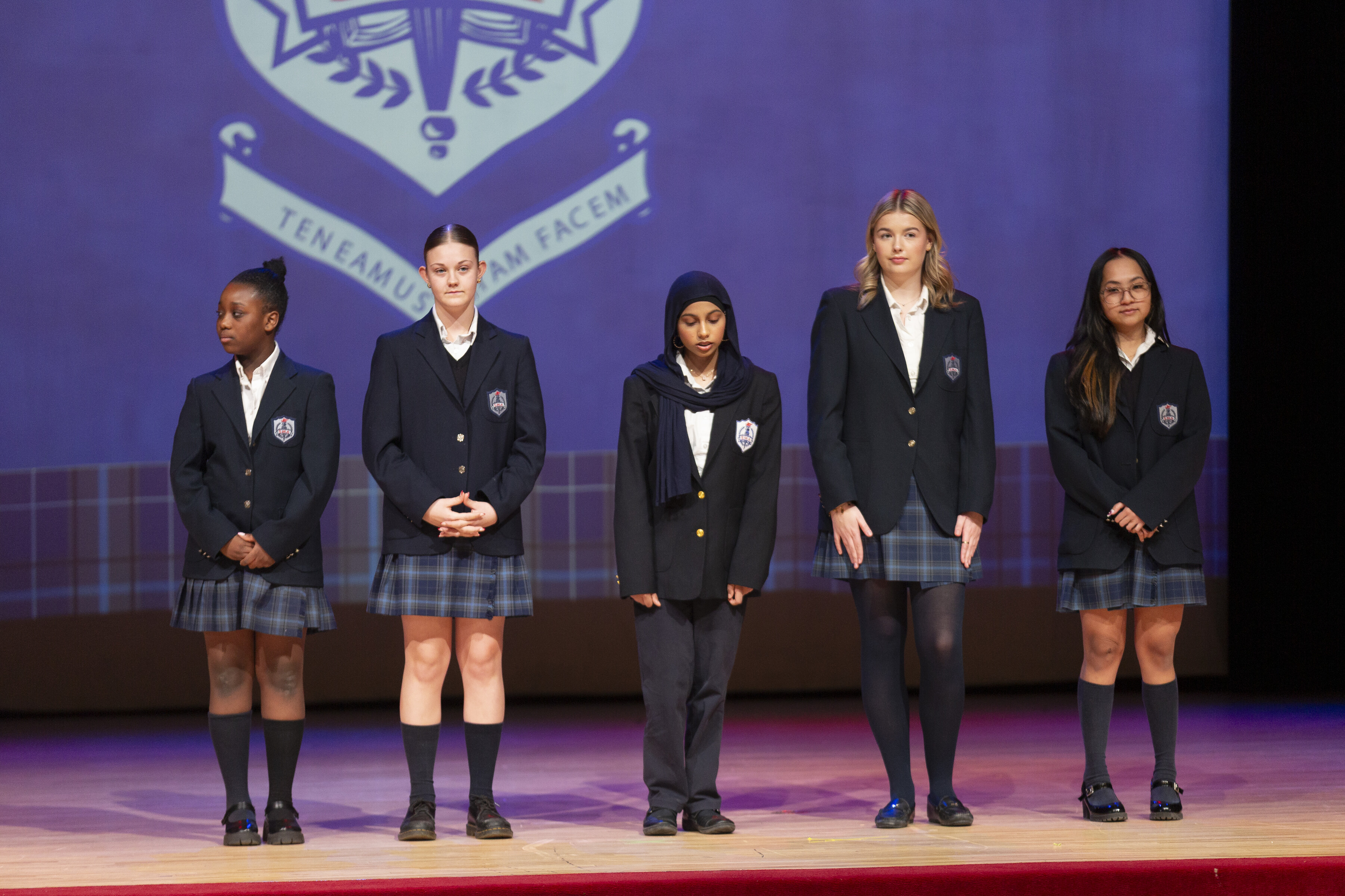 A group of St. Mary's Academy wearing their school uniforms in front of a stage
