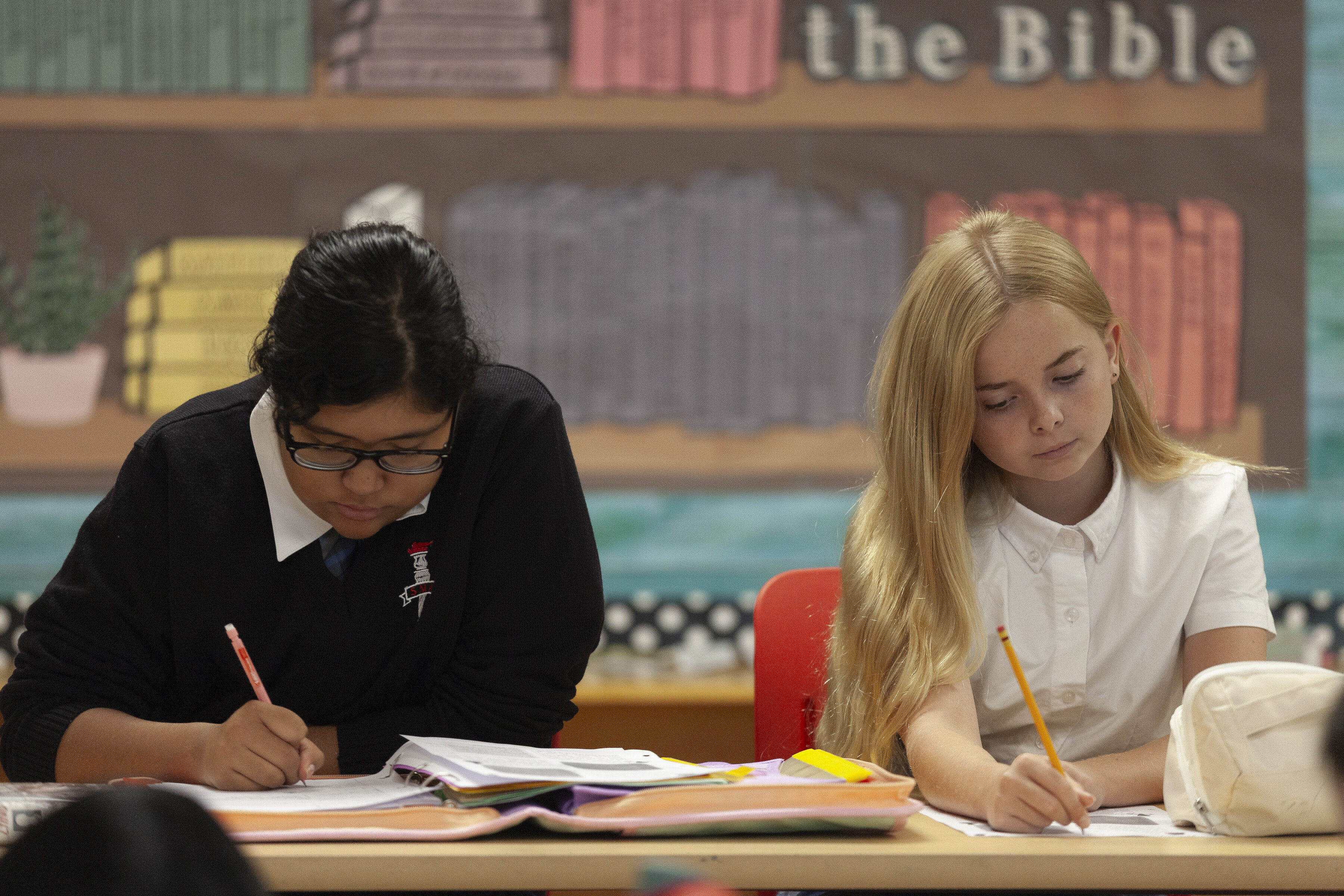 Two students studying in class and writing in their notebooks
