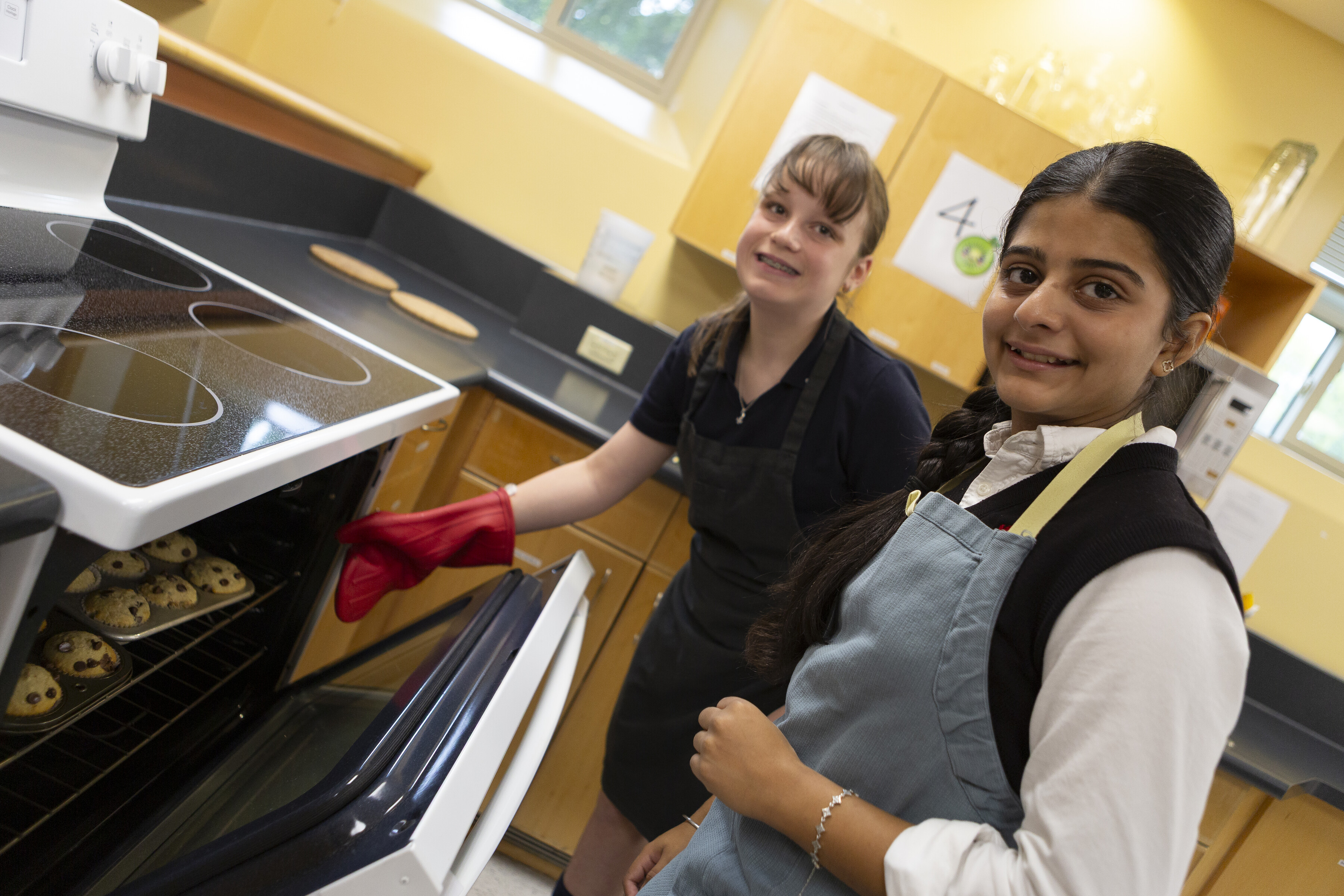 Two SMA students baking cookies while wearing aprons