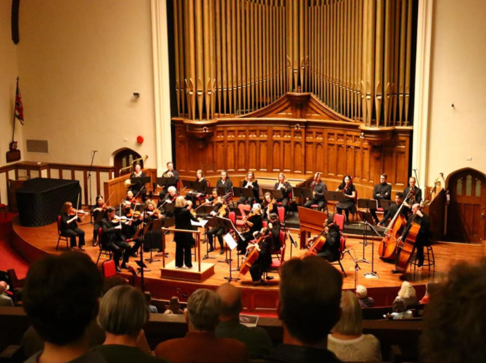 a group of people in a theatre listening to an orchestra performance