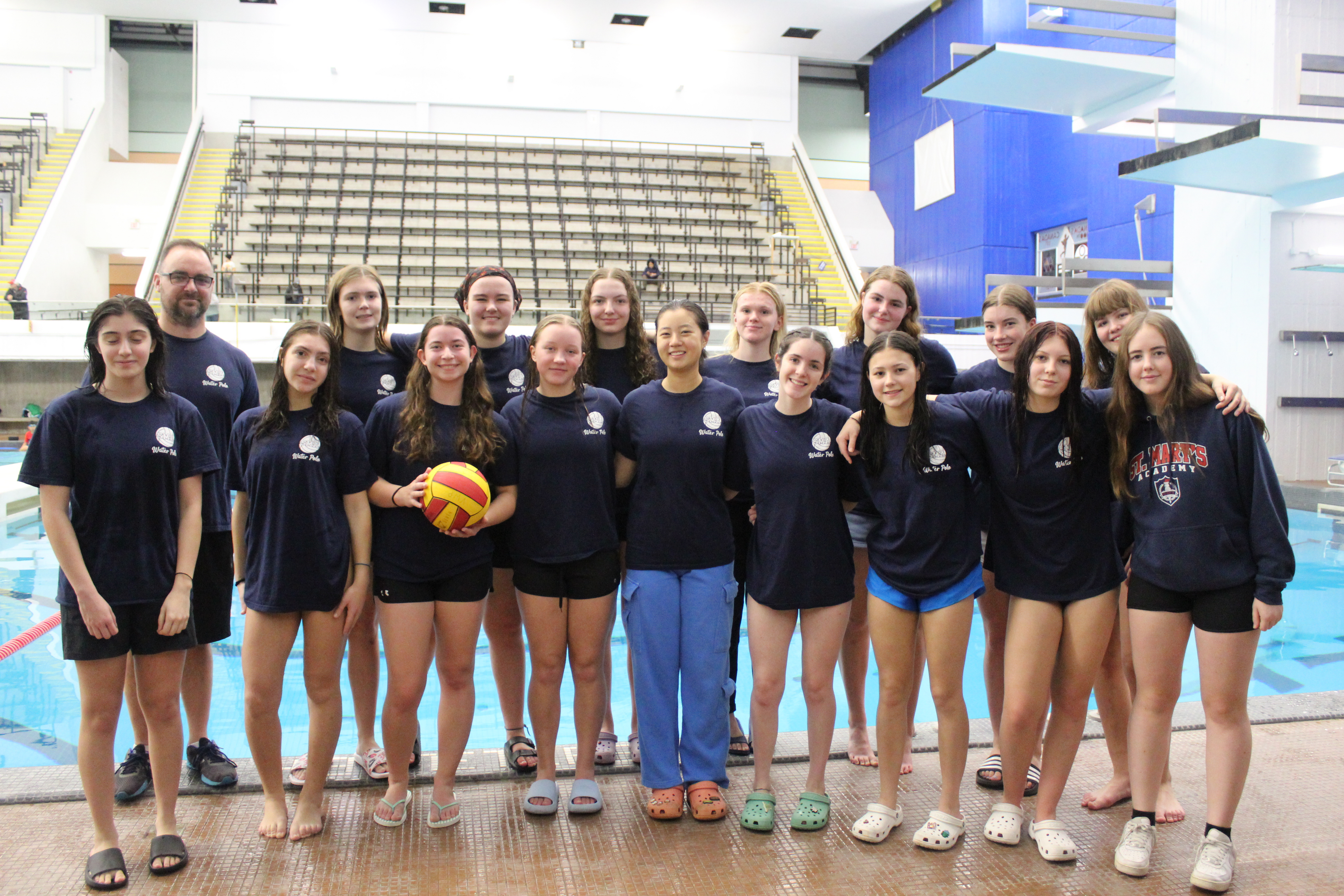 a group of women and a male teacher standing behind a swimming pool